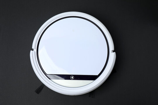 Robotic vacuum cleaner on laminate floor in living room. Smart cleaning technology.
