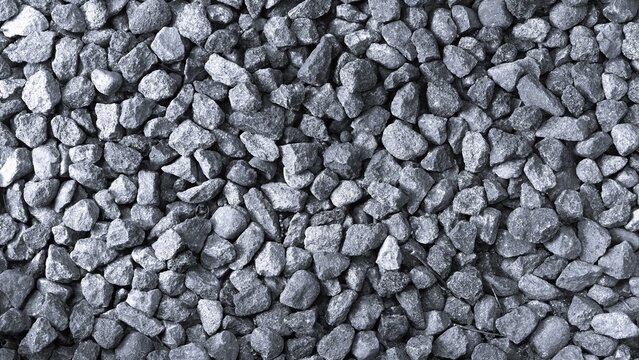 Monochrome close-up texture of coarse gray gravel stones, creating a natural rough surface pattern suitable for backgrounds, construction, landscaping, and abstract design.