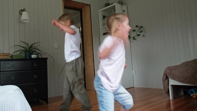 Happy active siblings exercising dancing together. Cute brother and sister jumping, doing fun sports routine. Fighting sedentary lifestyle in kids. Children physical health, energy wellness concept.