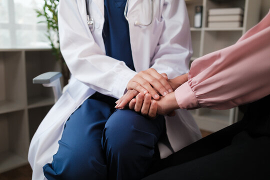 Doctor comforting patient holding hands during consultation