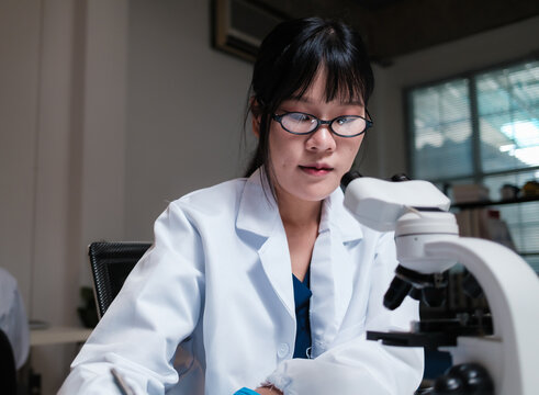 Asian woman scientist conducting research using microscope