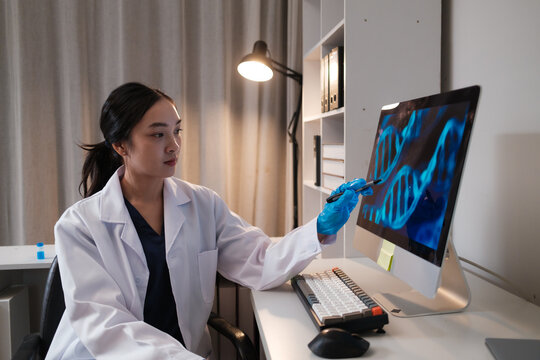 Female scientist analyzing DNA structure on computer monitor