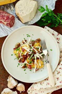 Overhead view of a assorted ingredients and a plate of traditional Italian Polenta with mushrooms, salami and smoked cheese