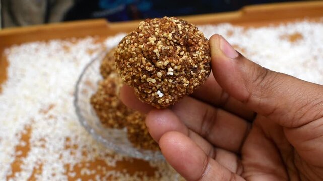 Hand holding puffed ramdana jaggery mithai, a wholesome Indian sweet and healthier alternative to store bought sweets, made with amaranth and natural jaggery.