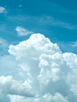 Vertical shot of a puffy cloud against clear blue sky