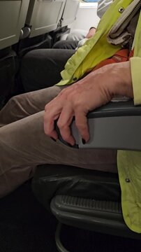 Hands resting on an airplane armrest during a flight