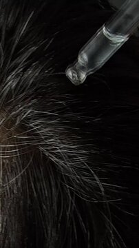 Applying serum to the scalp for hair growth and health in a close-up view