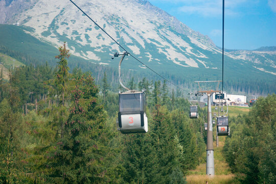 cable car line with cabins moving over green forest and high tatras mountains slovakia ropeway aerial transport outdoor landscape concept of travel adventure tourism recreation lifestyle