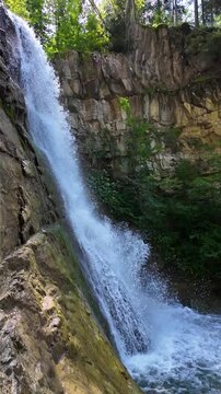 Water flowing in a waterfall on a sunny day. Slow motion