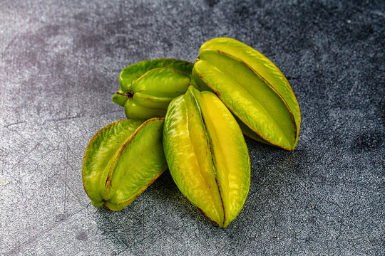 Fresh green star fruit on textured dark surface