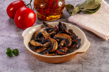 Fototapeta premium Grilled mushrooms in a ceramic bowl with fresh tomatoes and seasoned oil