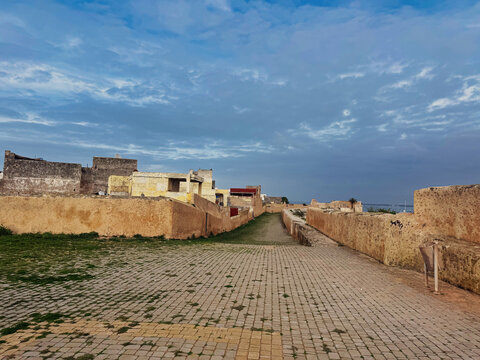 Weathered sandstone bastion walls with rounded sentry towers surround a cobblestone courtyard inside the Portuguese fortress of El Jadida, Morocco.