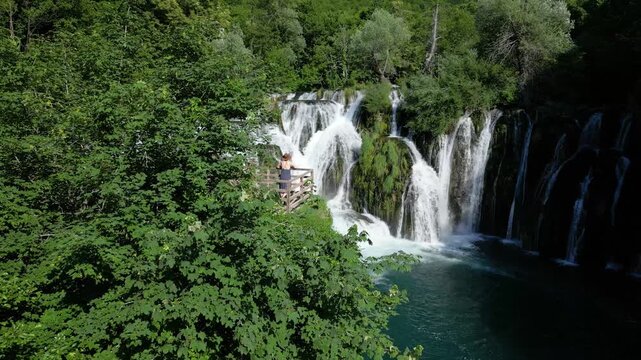 Drone View of Woman Admiring Martin Brod Waterfalls in Una National Park, Bosnia and Herzegovina Surrounded by Nature
