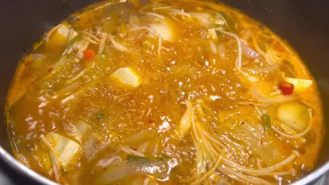 Korean Kimchi Jjigae Simmering in Cooking Pot with Tofu and Vegetables