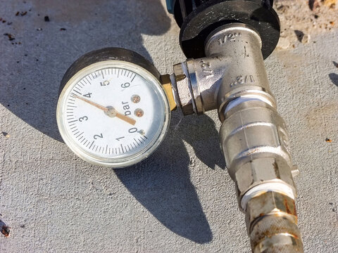 Pressure gauge on a metal pipe displays about 3 bar on the concrete, close-up showing system control.