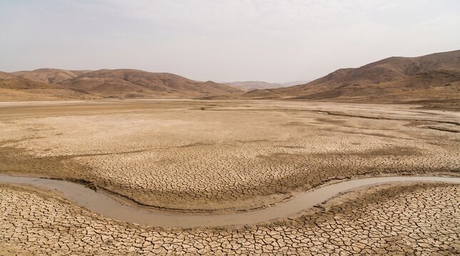 Cracked Earth Landscape with Dry Riverbed and Distant Hills