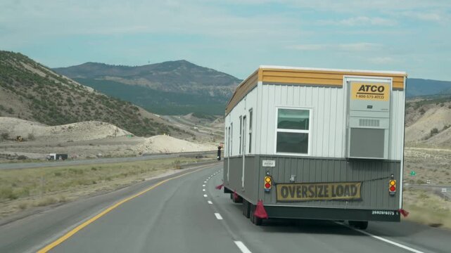 Oversize truck transporting a modular plastic house through the United States, highlighting manufactured home transportation, affordable housing, logistics and the growing modular housing industry