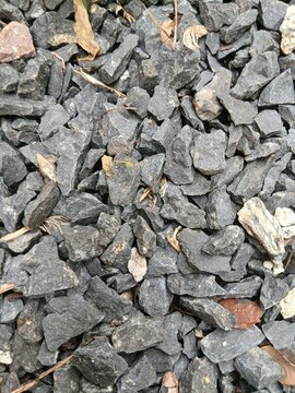Detailed top view of grey crushed granite gravel, sharp rubble stones, and small pebble aggregate surface background for construction or landscaping design.