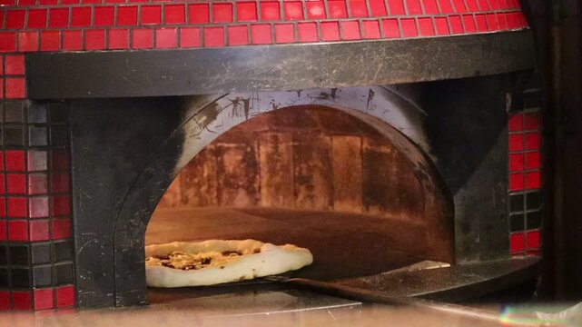 Pizza Being Placed Into a Wood-Fired Oven