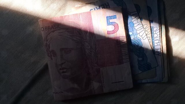 Brazilian five reais banknotes moving in a soft light motion clip