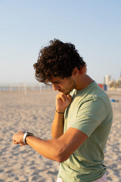 A Young Athlete Checks His Heart Rate After Exercising on the Beach