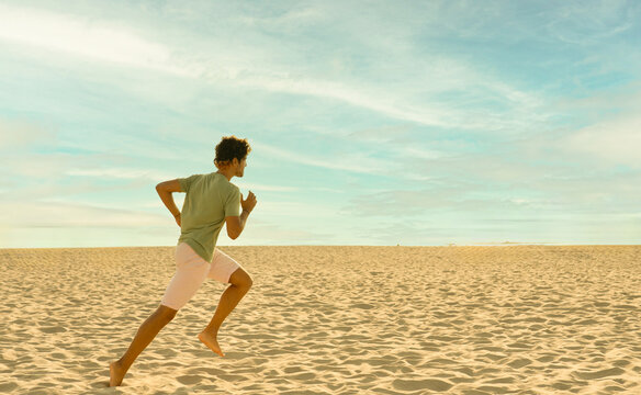 Young person running barefoot on the beach outdoors