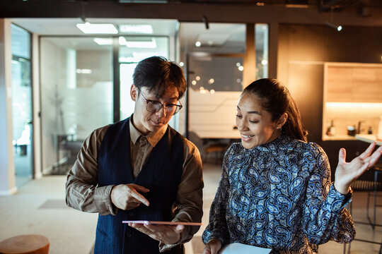 Coworkers discussing project on tablet in modern office