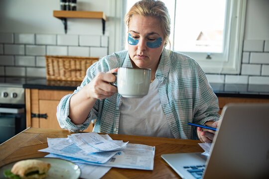 Woman managing household bills with coffee in kitchen
