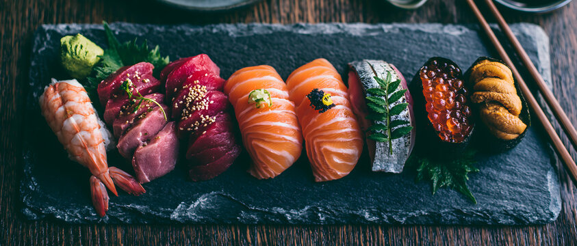 Assorted sushi and sashimi pieces arranged on a slate serving platter cuisine japanese food nigiri maki raw fish seafood shrimp salmon tuna sea
