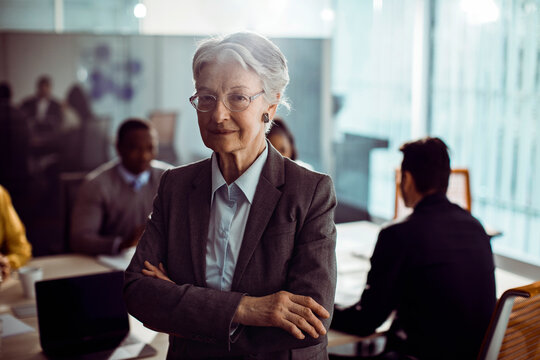 Confident senior businesswoman leading team in modern office