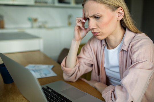 Worried woman reviewing finances on laptop at home