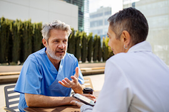 Two healthcare professionals discussing patient care in hospital courtyard
