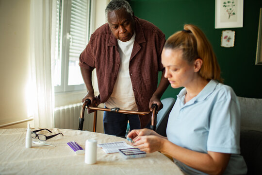 Caregiver preparing medication for senior man at home