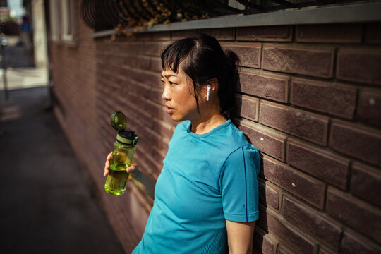 Woman runner cooling down with water bottle on urban street