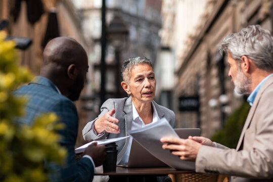Senior business colleagues discussing documents at outdoor cafe