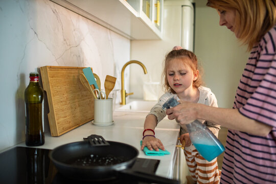 Mother and daughter cleaning kitchen countertop at home