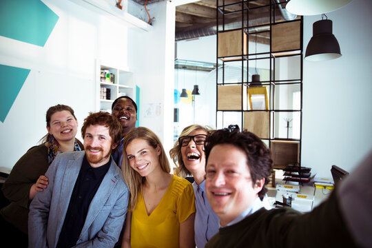 Diverse coworkers taking a cheerful selfie in modern office