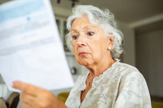 Concerned senior woman reading a bill at home