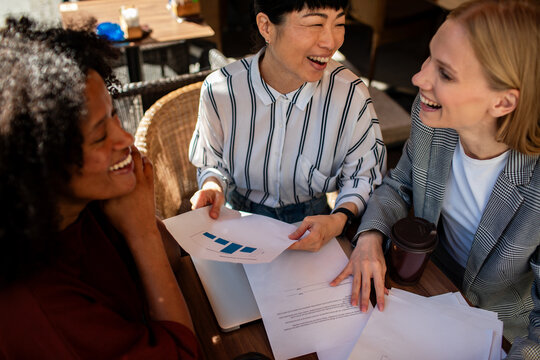 Three businesswomen discussing charts at outdoor cafe