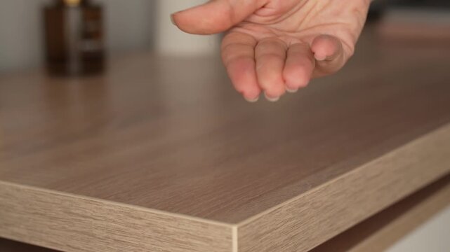 Young woman wiping wooden tabletop with hand and showing dust on fingers, dirty surface and household cleaning problem in home interior, close-up