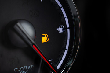 Naklejka premium Fuel gauge with warning indicating low fuel tank on car dashboard