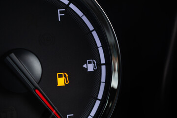 Naklejka premium Fuel gauge with warning indicating low fuel tank on car dashboard