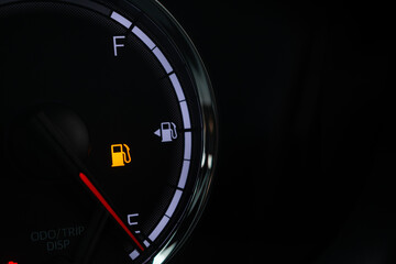 Fototapeta premium Fuel gauge with warning indicating low fuel tank on car dashboard
