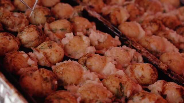 Chef picking up octopus takoyaki, a popular Japanese Osaka street food for tourists