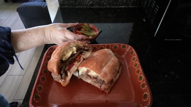 Person serving delicious mexican milanese torta sandwich with pickled peppers