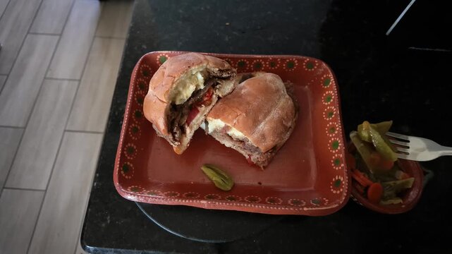 Person eating traditional mexican torta de milanesa sandwich with pickled jalape&ntilde;os
