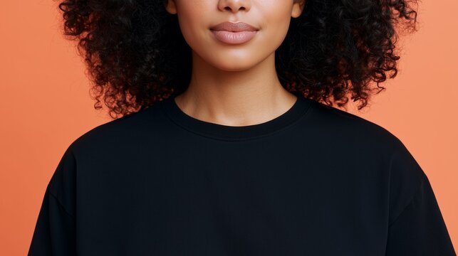 Woman Wearing Blank Black T-Shirt on Orange Background, Excellent for Apparel Branding, Print-on-Demand Design and Fashion Merchandise Mockups