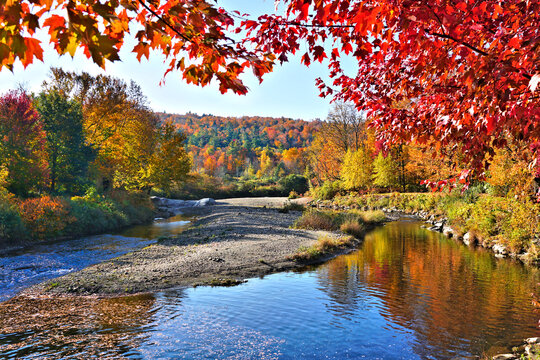 Beautiful autumn colors along a river with reflections in the countryside of Vermont, USA