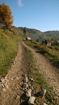 Dirt road winding through rural mountain village in autumn