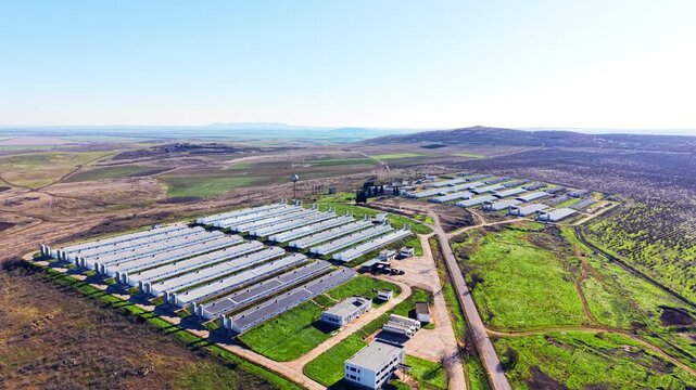 Scenic aerial view of poultry farm complexes, Bulgaria. Parallel barn rows spread across farmland with hills rising in the distance.